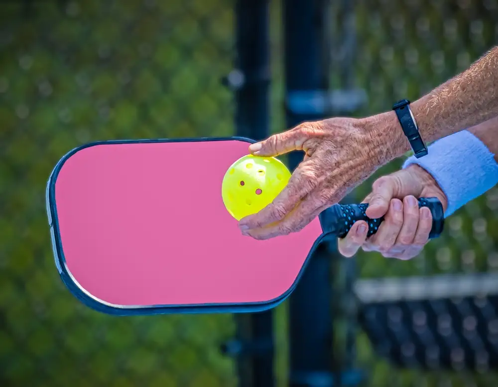 Lady hand holding ball pickleball near paddle getting ready to serve