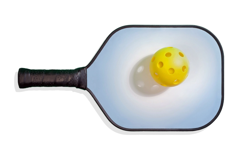 Pickleball paddle with ball resting on top